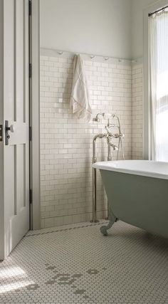 a bath tub sitting next to a white door in a bathroom with tile flooring