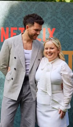 a man and woman standing next to each other in front of a sign that says netflix