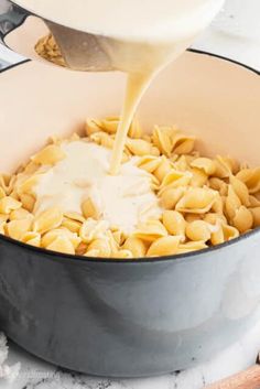 a pot filled with macaroni and cheese being poured into it