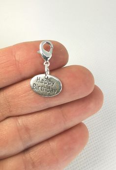 a person holding a happy birthday charm in their hand