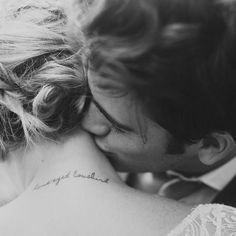 a man and woman kissing each other with tattoos on their backs