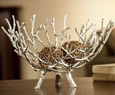 a small bowl with branches in it sitting on a table next to a bookshelf