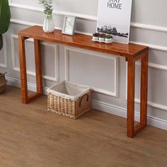 a wooden table sitting in front of a white wall next to a potted plant