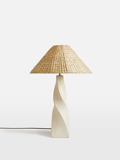 a lamp that is sitting on top of a table with a straw hat on it