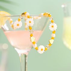 a glass with a drink in it next to a lemon slice and some beads on the rim