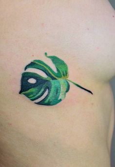 a green leaf tattoo on the side of a woman's right arm and chest