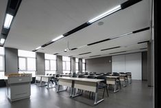 an empty classroom with desks and chairs in front of large windows on the wall