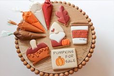 decorated cookies are arranged in the shape of pumpkins for sale on a wooden platter