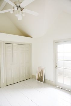 an empty room with white floors and ceiling fan