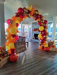 an arch made out of balloons and pumpkins is decorated with welcome fall sign in the center