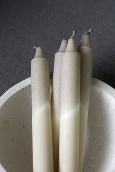 three candles are in a white bowl on the floor