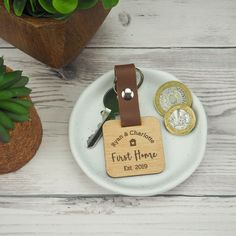 a personalized wooden keychain is on a plate with two coins and a plant