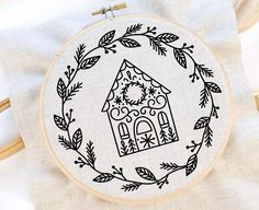 a cross stitch pattern with a house in the middle and leaves around it on a white background