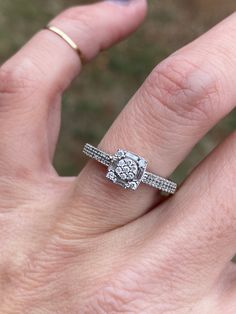 a woman's hand with a diamond ring on top of her finger and the other hand holding an engagement ring