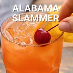 someone holding a cherry and orange drink with the words, alabama slamer above it