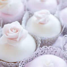 several cupcakes with white frosting and a pink rose on the top one