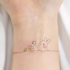 a small tattoo on the wrist of a woman's arm with a bunny and flower