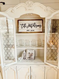 the hutch is decorated with white furniture and glassware, including an old fashioned cabinet