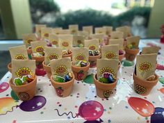 there are many small pots with candy in them sitting on the tablecloth at this birthday party