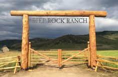 a wooden gate with the word bed rock ranch on it in front of a field