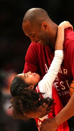 a man holding a basketball while standing next to a woman on top of a basketball court