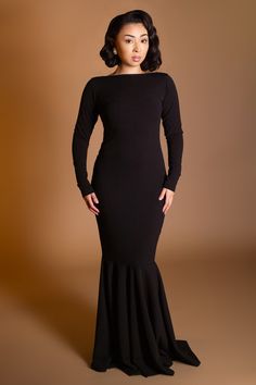 a woman in a black dress posing for the camera with her hands on her hips