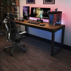 a desk with a computer monitor, keyboard and mouse on it in front of two pictures