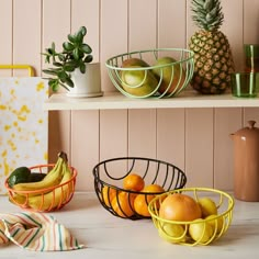 fruit in baskets on shelves next to potted plants and other kitchen items, such as pineapples