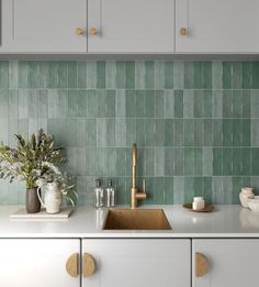 a kitchen with green tiles on the backsplash and gold faucet handles