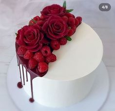 a white cake with raspberries and chocolate drizzled on the top