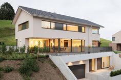 a modern house on a hillside with two garages