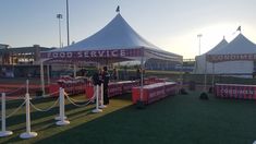 tents set up in the grass with people standing under them at an outdoor food service event