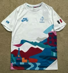 a white nike shirt with blue and red designs on the front, sitting on a carpet