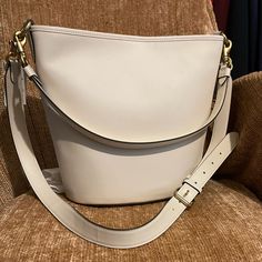 This Iconic Archival Dakota Bucket Bag In A Relaxed Coach Style Is The Epitome Of Laid-Back Sophistication. The Buttery Soft Glovetanned Leather Style Has A Spacious Interior And Is Finished With Two Detachable Straps To Carry By Hand, Style As A Short Shoulder Bag Or Wear Crossbody. (It’s Totally Up To You.). It Equipped With A Inside Zip Pocket And A Snap Closure To Keep Your Things Safe & Secure. Detachable Handle With 10 3/4" Drop Detachable Strap With 21 1/2" Drop For Shoulder Or Crossbody Classic Beige Bag For Everyday Luxury, High-end Beige Bucket Bag, Classic Cream Bag For Everyday Luxury, High-end Daily Use Bucket Bag With Gold-tone Hardware, High-end White Bag With Adjustable Strap, Cream Top Handle Shoulder Bag For Everyday, Classic Bucket Bag With Detachable Strap In Tote Style, Classic Bucket Bag With Detachable Strap And Tote Shape, High-end Bucket Bag With Detachable Handle For Everyday