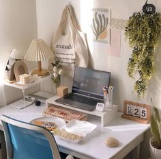 a laptop computer sitting on top of a white desk next to a blue chair and potted plant