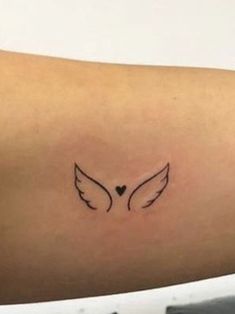 a woman's arm with an angel wing tattoo on the back of her shoulder