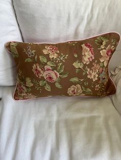 a pillow with flowers on it sitting on top of a white bedding set and pillows