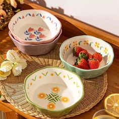 three bowls with strawberries in them sitting on a table next to sliced lemons