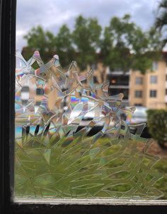 a window that has some kind of glass on the side of it with trees and buildings in the background