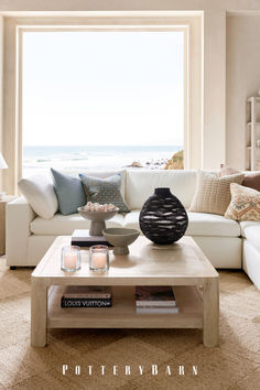 a living room filled with furniture and a large window overlooking the ocean in front of it