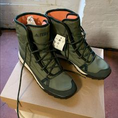 a pair of green shoes with tags on them sitting on top of a cardboard box