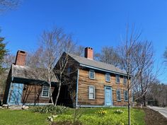 an old wooden house with blue shutters on the front and side windows, surrounded by trees