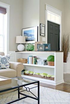 a living room filled with furniture and pictures on top of the bookshelves in front of a window