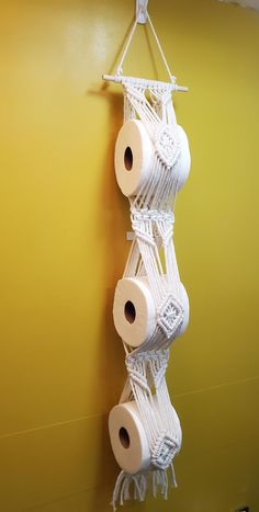 three rolls of toilet paper hanging from a rope on a wall with yellow walls in the background