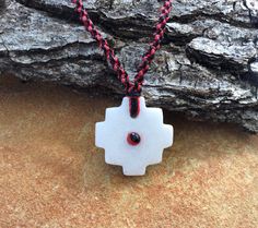 a white and red necklace on a rock