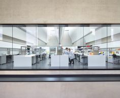 an office with glass walls and people working at desks in the middle of it