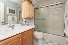 a bathroom with blue and white checkered flooring, wooden cabinetry, and a walk in shower