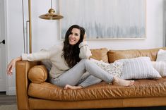 a woman sitting on top of a brown couch