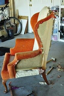 an old chair sitting in a garage next to a bike and other items on the floor