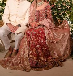 a man and woman sitting next to each other in front of a flower covered wall